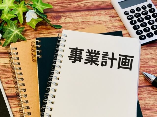 机上の事業計画ノートと電卓